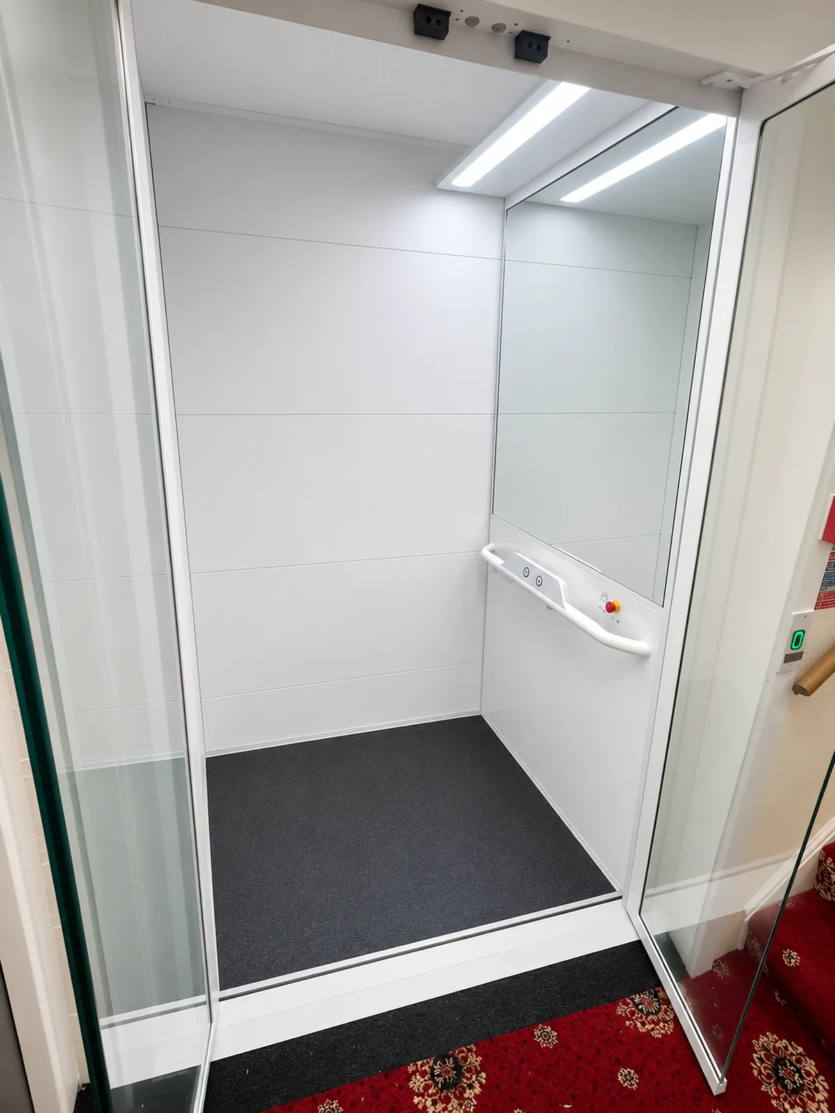 Bright modern lift cabin with handrail and simple controls