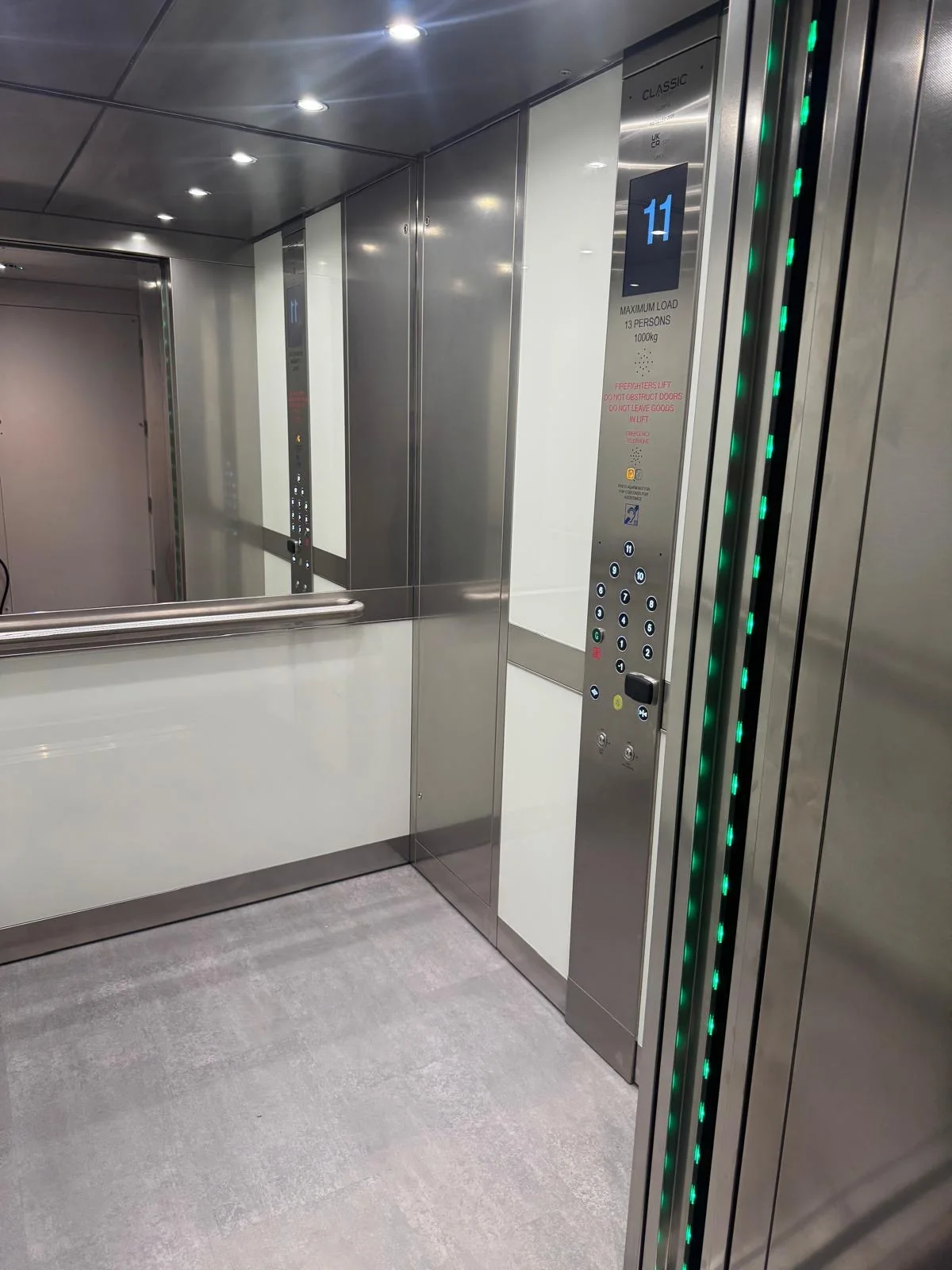 Inside the new lift car: a mirror on the rear wall, white glass side panels, a stainless handrail and LED downlights