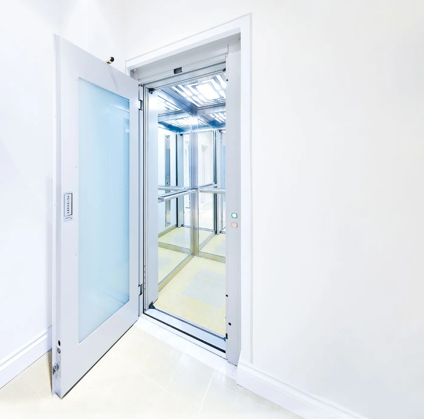 A white hinged landing door with a frosted glass panel open onto a bright cabin with polished steel walls, a handrail and a lit ceiling