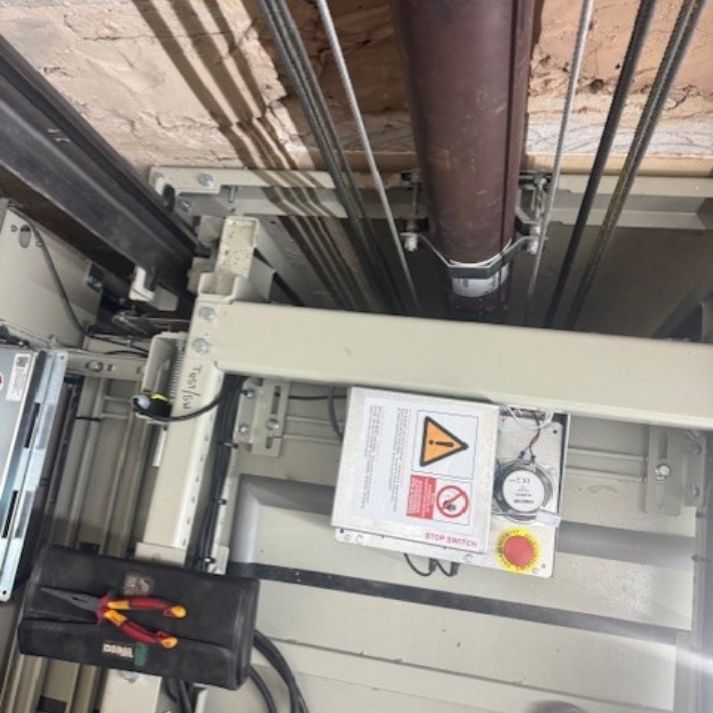Looking down a lift shaft during a service visit, with the car top control panel and stop switch exposed
